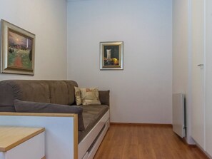 A small living area with a sofa, a table, and two framed pictures on the wall. - Saariseläntie 8 b 7 by Interhome (Inari)