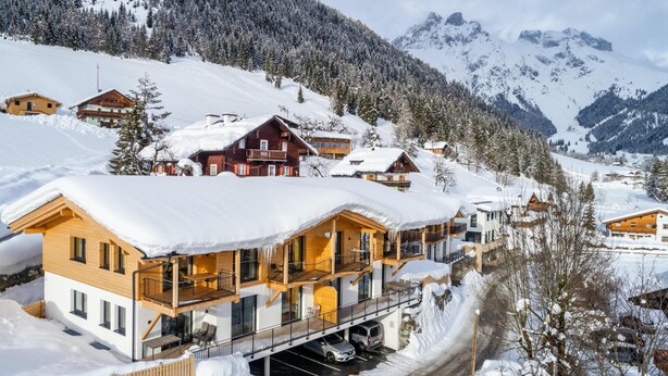 A snow-covered mountain village with wooden houses and a ski lift.