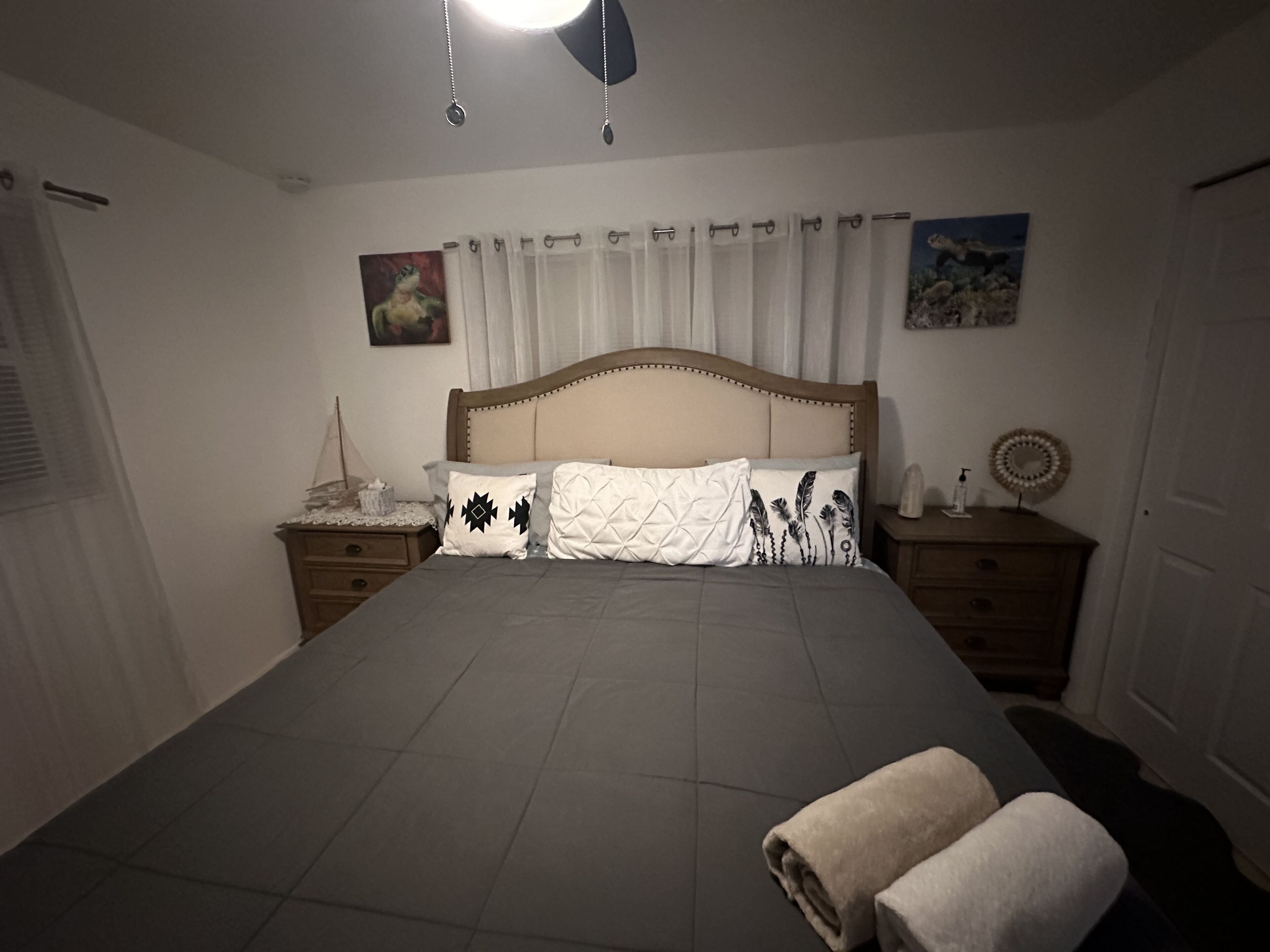 Een slaapkamer met een groot bed, een houten hoofdbord, een nachtkastje met een lamp en een aan de muur hangend schilderij.