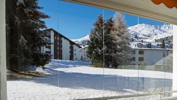 Aussicht auf eine verschneite Landschaft mit Gebäuden und einem Berg im Hintergrund.