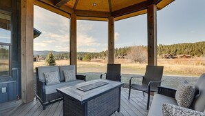 A covered outdoor seating area with wicker furniture and a view of a forested landscape. - Spacious McCall Home w/ Private Lake Access! (McCall)