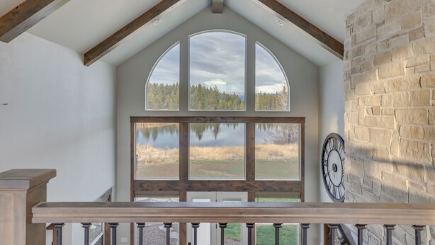 A spacious room with a large arched window, a stone wall, and a wooden ceiling beam. - Spacious McCall Home w/ Private Lake Access! (McCall)