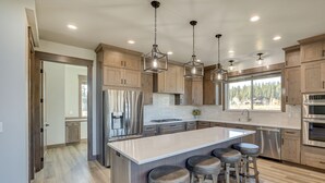 A modern kitchen with wooden cabinets, stainless steel appliances, and a central island with bar stools. - Spacious McCall Home w/ Private Lake Access! (McCall)