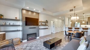 A modern living room with a fireplace, a dining area, and a kitchen with wooden cabinets and pendant lighting. - Suncadia Resort Condo: Balcony & Golf Course Views (Cle Elum)