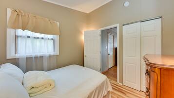 A bedroom with a bed, a wooden dresser, and two white doors leading to other rooms.