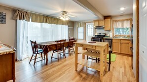 A spacious kitchen with wooden cabinets, a dining area with a wooden table and chairs, and a ceiling fan. - Salem Vacation Home w/ Dock: Steps to Paddock Lake (Salem)