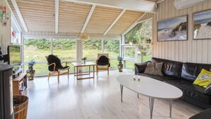 A spacious living room with a wooden ceiling, large windows, a black leather sofa, and a round coffee table. - "Immi" - 1.5km from the sea by Interhome (Saltum)