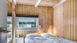 A bedroom with a bed, a window, and a white nightstand with a teal vase. - "Immi" - 1.5km from the sea by Interhome (Saltum)