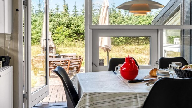 A dining area with a table, chairs, a red vase, and a view of the outdoors. - "Immi" - 1.5km from the sea by Interhome (Saltum)