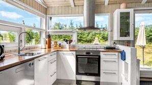 A modern kitchen with white cabinets, a stainless steel range hood, and a large window overlooking greenery. - "Immi" - 1.5km from the sea by Interhome (Saltum)