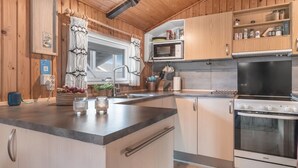 Una cocina moderna con armarios de madera, una isla central, microondas integrado y horno Voss.