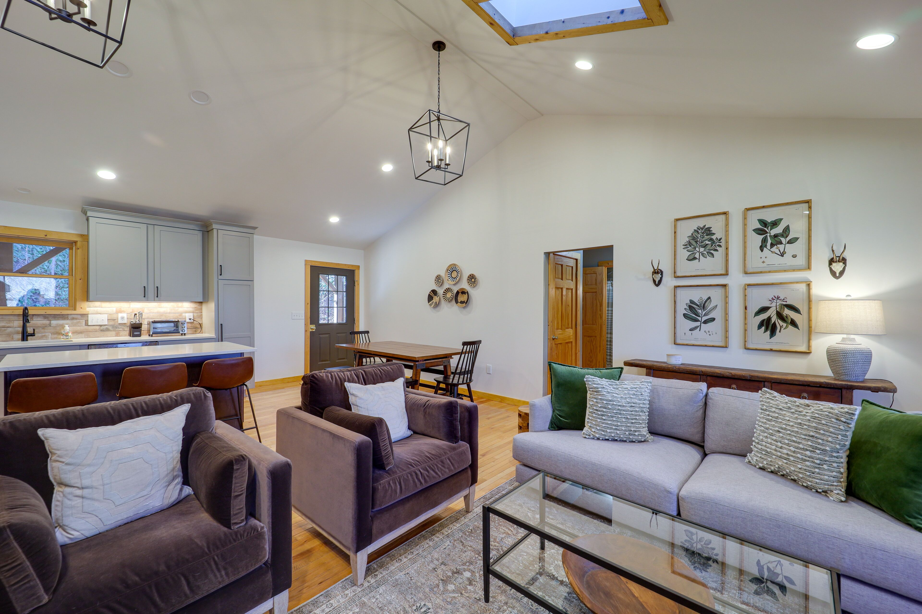 A spacious living area with a kitchen in the background, a dining table, and a sofa set.