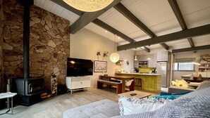 A cozy living room with a stone fireplace, a flat-screen TV, and a comfortable sofa.