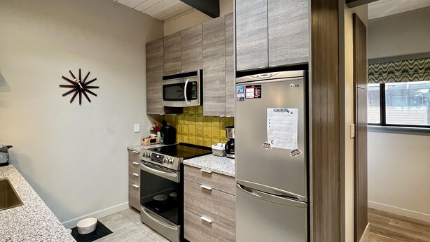 A modern kitchen with a skylight, built-in appliances, and a granite countertop.