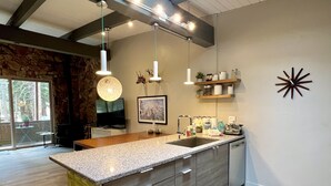A modern kitchen with a large island, pendant lights, and a skylight.