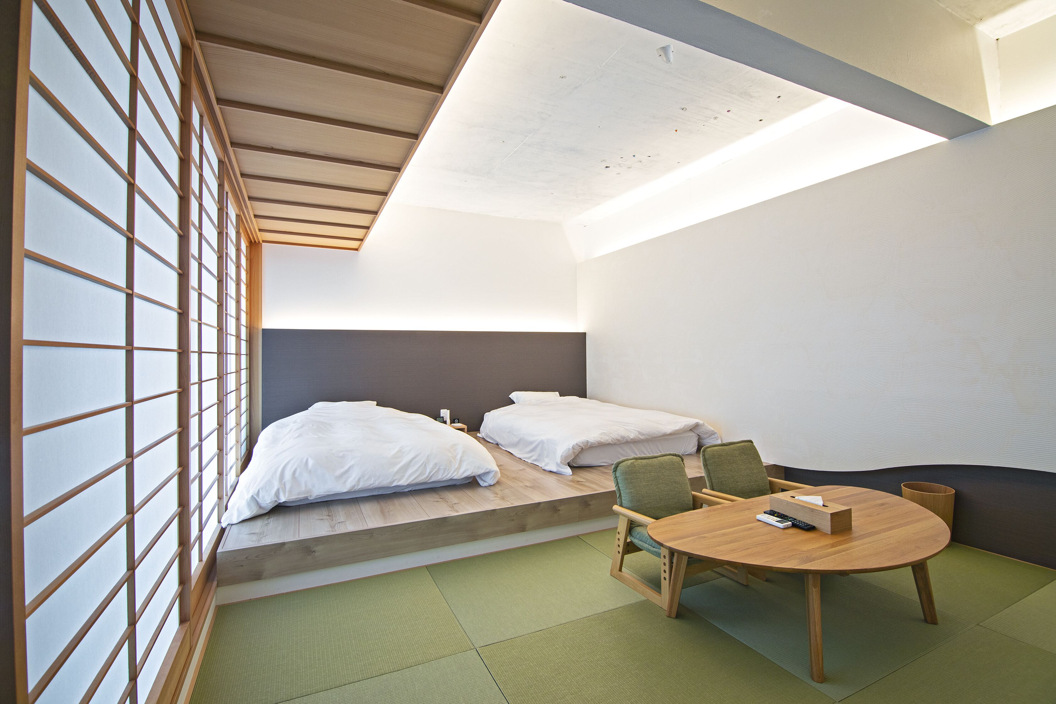 A room with two beds, a dining table, and a green mat on the floor.