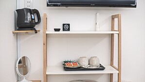 A hotel room with a TV, a coffee machine, a mirror, a shelf with toiletries, and a trash bin. - Forest Guardian Hotel 京都御所西 (Kyoto)