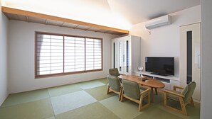 A room with tatami mats, a television, cabinets, and a sliding door. - Forest Guardian Hotel 京都御所 西 (Kyoto)