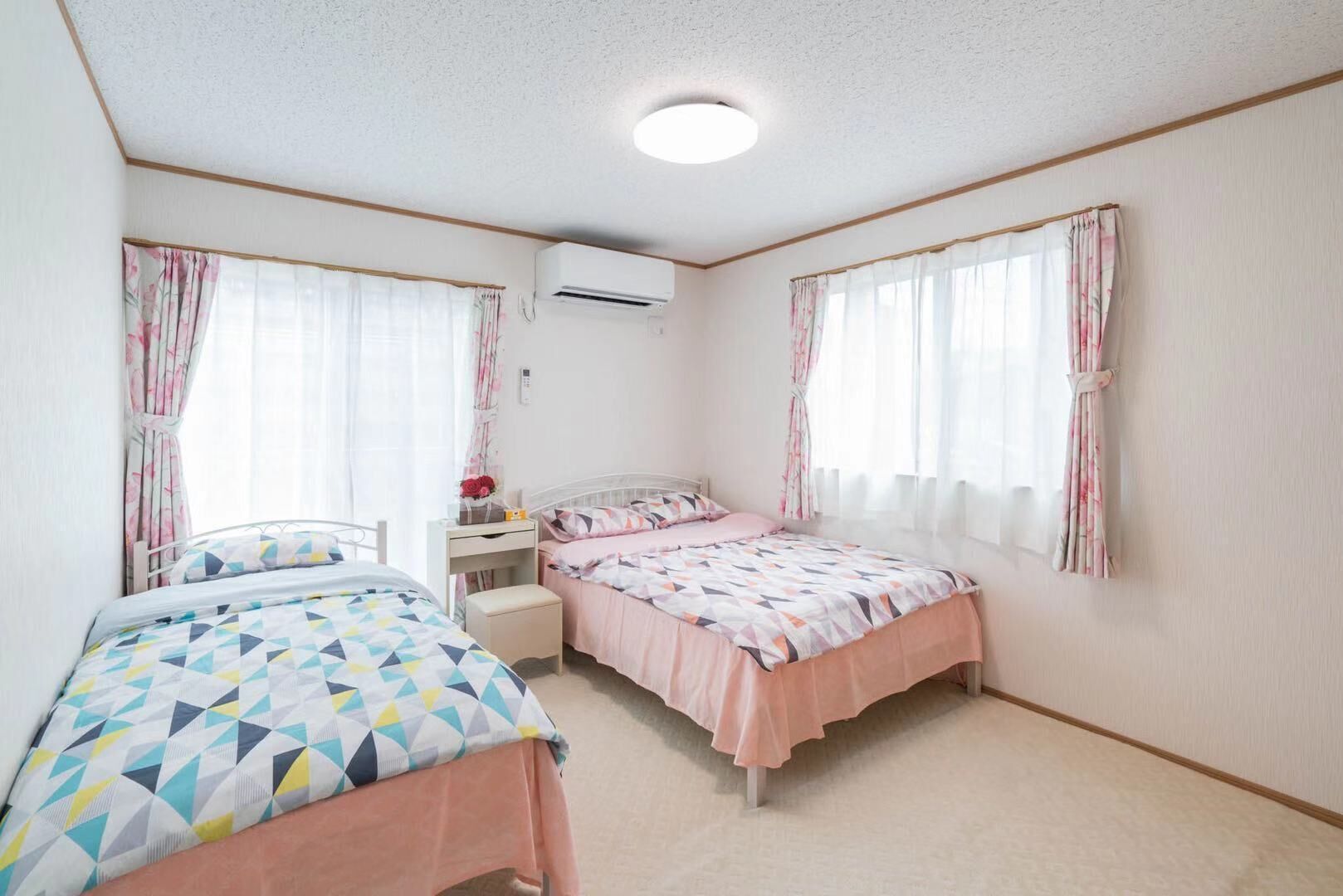 Une chambre avec deux lits, une table de chevet et un climatiseur.