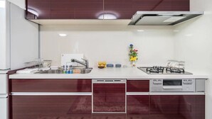 Una cocina moderna con armarios de madera oscura, una encimera blanca, una estufa a gas y un lavavajillas.