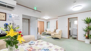 Una habitación con mantel a cuadros, un sofá y una silla. Hay un jarrón con flores sobre la mesa.