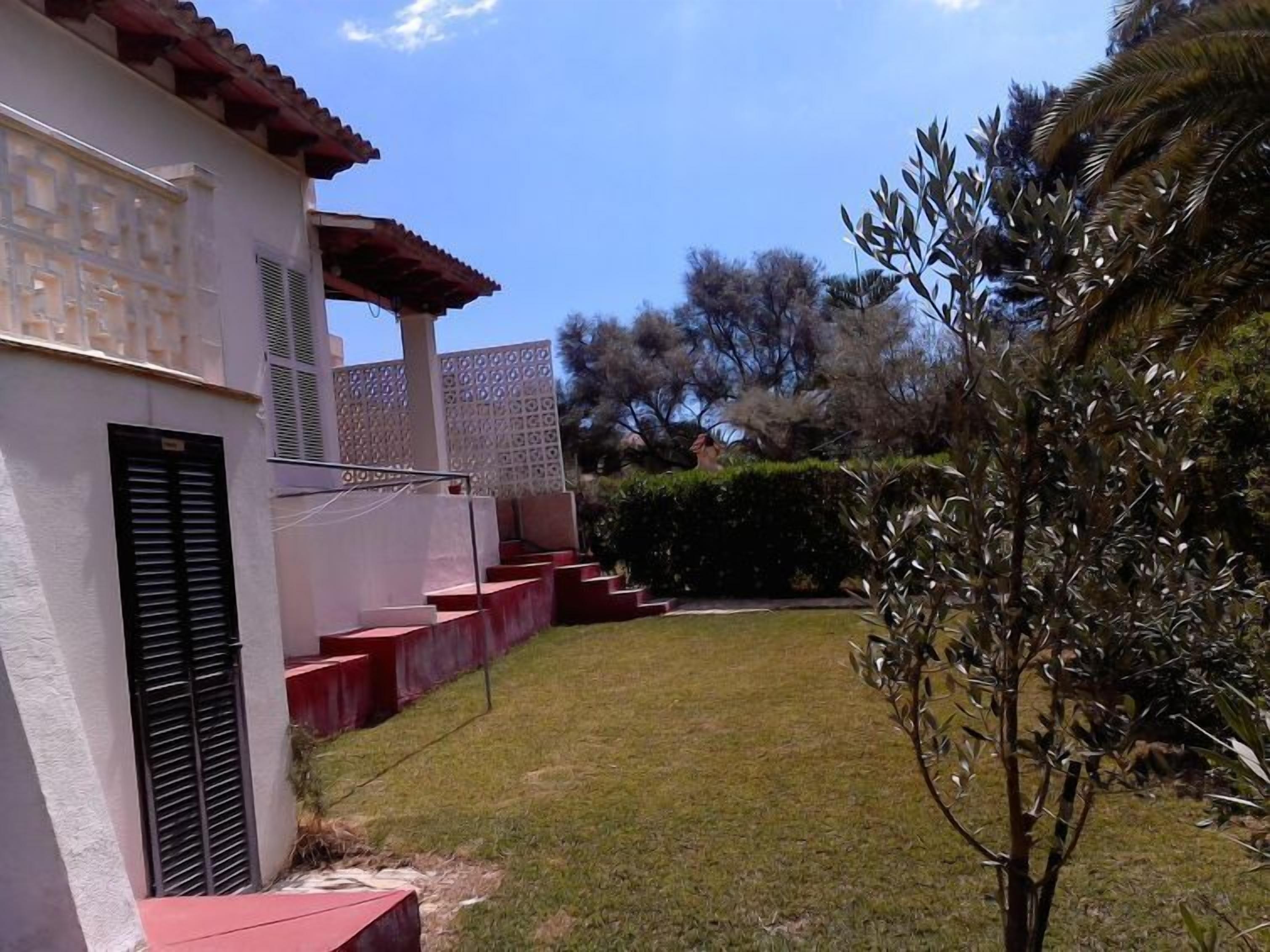 Un edificio con tetto rosso, pareti bianche e un piccolo prato.