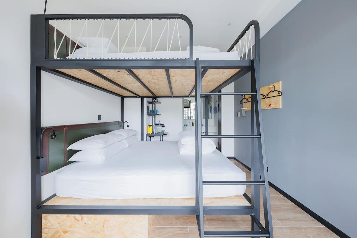 Una litera con una escalera, un cabecero de madera y un estante con artículos de aseo.