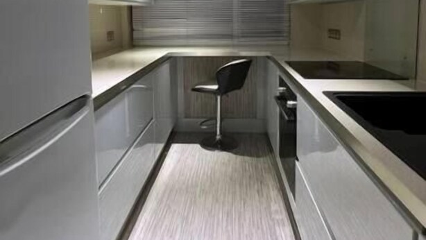 A narrow kitchen with a stainless steel refrigerator, a black chair, and a window with blinds. - Charming 2bedroom Retreat in Great Barr/hamsted (Birmingham)