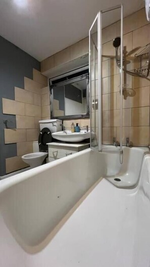 A modern bathroom with a bathtub, a sink, and a toilet. - Charming 2bedroom Retreat in Great Barr/hamsted (Birmingham)