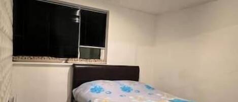 A bedroom with a bed, a window, and a patterned ceiling.