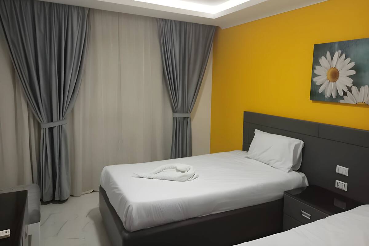A hotel room with a bed, bedside table, and a nightstand.