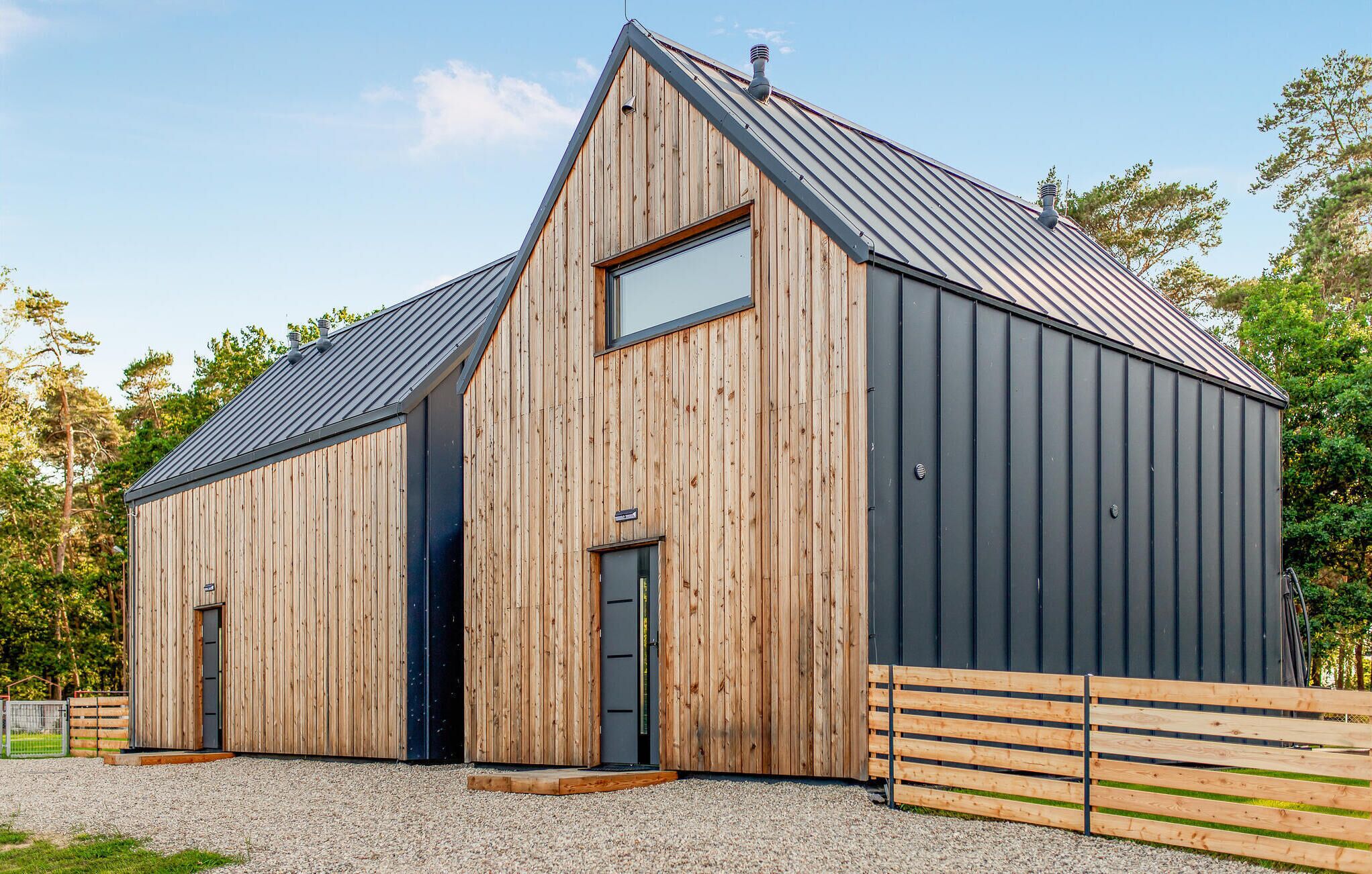A wooden barn with a metal roof, a large window, and a door.