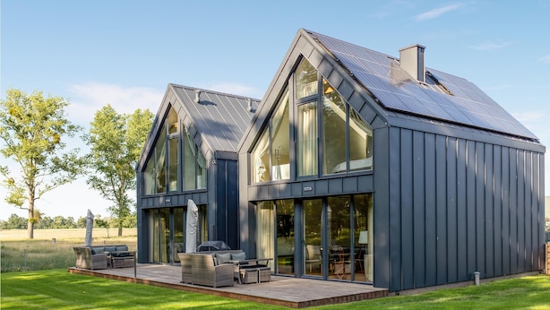 A modern house with large windows, a deck, and solar panels.