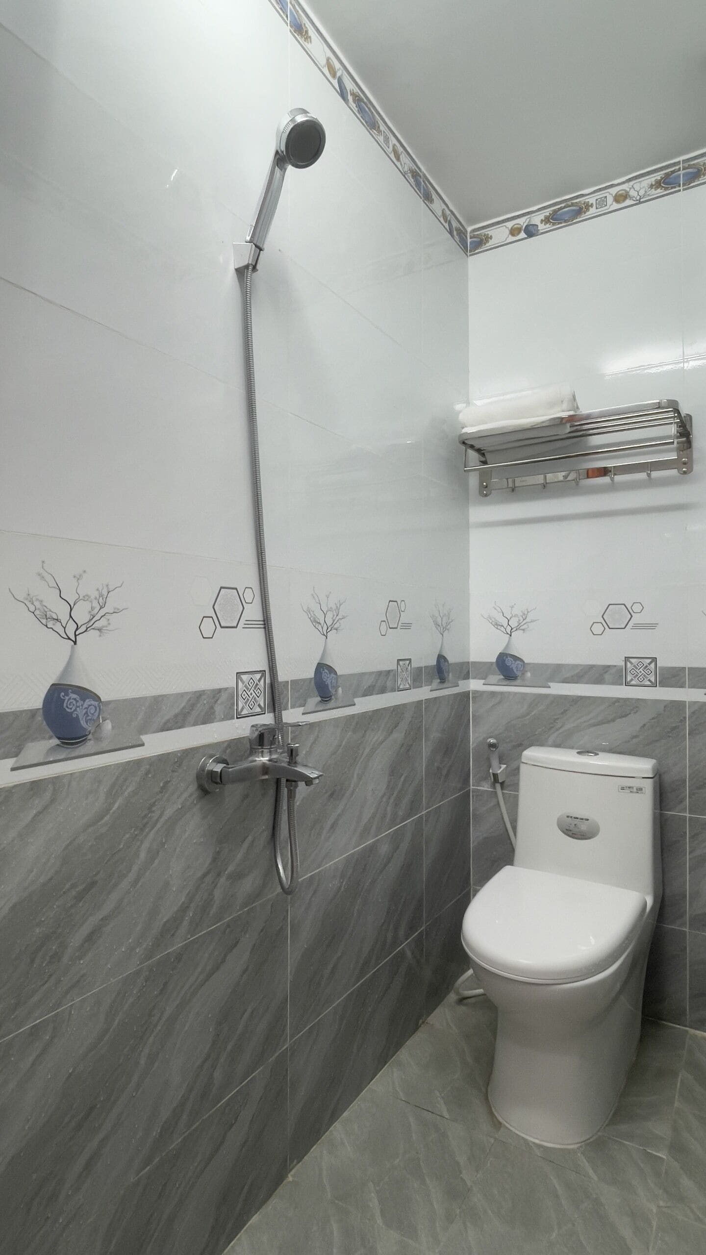 Een badkamer met toilet, douche en een plank met decoratieve vazen.