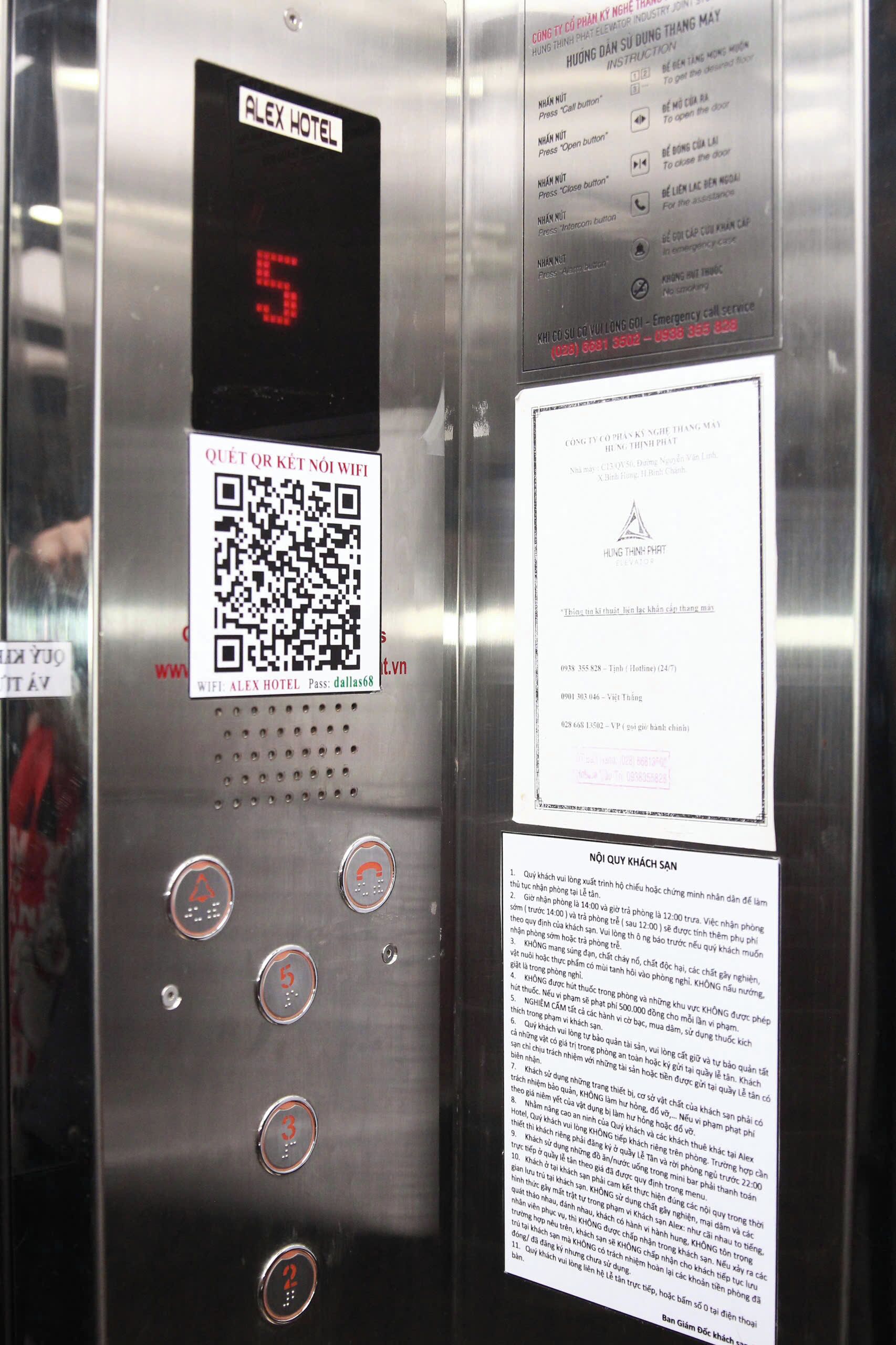 Panel de control de ascensor con pantalla digital, un código QR y un punto de acceso Wi-Fi para el Hotel Alex.