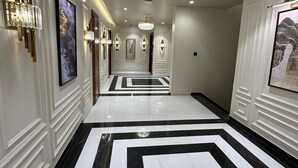 A hallway with a black and white marble floor, wall-mounted light fixtures, and framed artwork. - THE LOVE PASSION KARMA CLUB & RESORT (Udaipur)