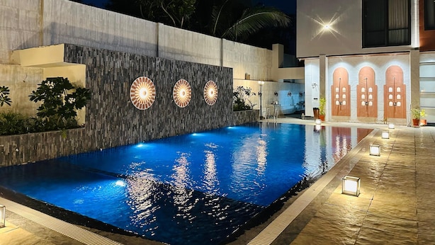 A swimming pool with a modern design, surrounded by a concrete wall with decorative lighting. - THE LOVE PASSION KARMA CLUB & RESORT (Udaipur)
