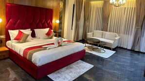 A hotel room with a large bed, a sofa, a chandelier, and a ceiling fan. - THE LOVE PASSION KARMA CLUB & RESORT (Udaipur)