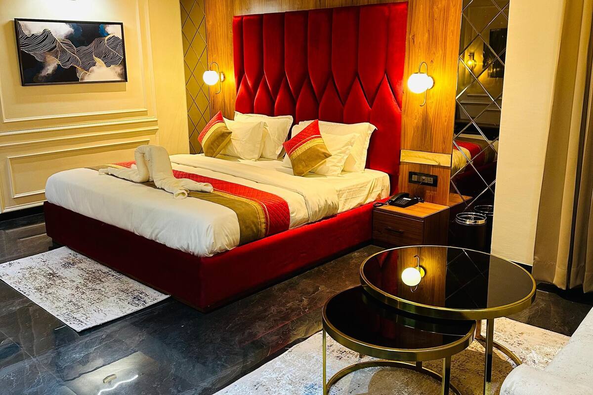 A modern bedroom with a red bed, a round black table, and a wooden headboard.