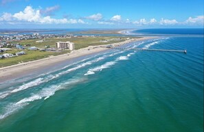 An aerial view of a coastal area with a beach, a pier, and a large hotel. - Rock the Boat by AvantStay | 5 Blocks to Beach (Port Aransas)