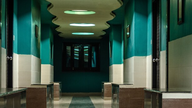 Un couloir aux murs de couleur turquoise, doté d’un sol en marbre et d  ’un éclairage encastré.