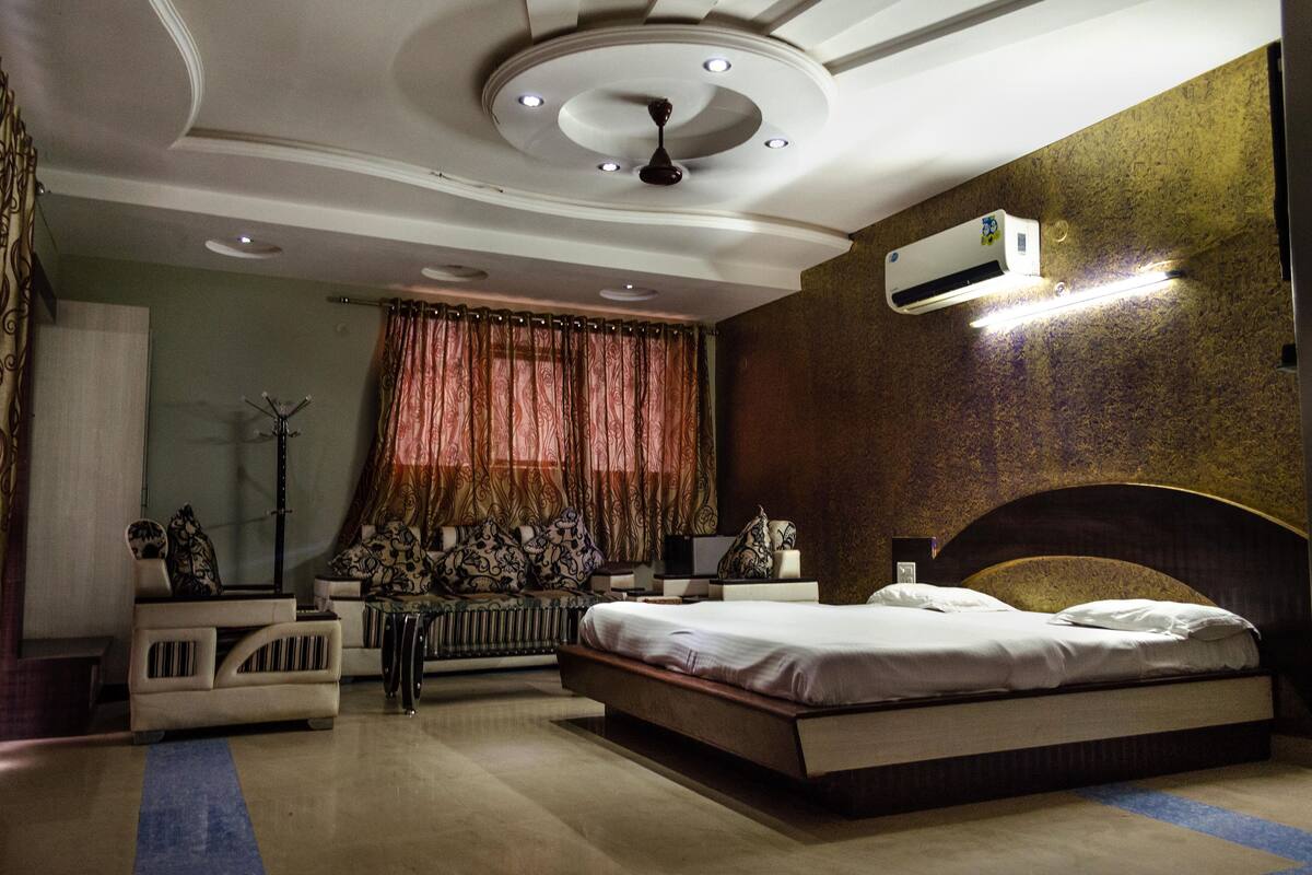 A bedroom with a bed, a sofa, a radiator, and a ceiling fan.
