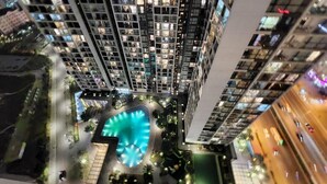 A high-rise building with multiple floors, a central courtyard with a blue swimming pool, and surrounding greenery. - Vinhome Skylake Luxury Apartment  (Hanoi)