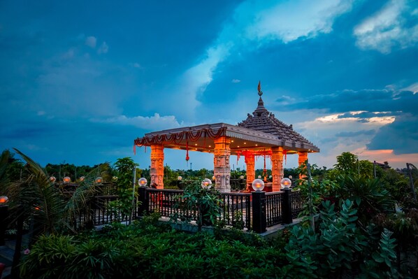 A gazebo with a tiled roof and a spire, surrounded by lush greenery. - Mayfair Purnea (Purnia)