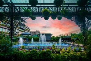 A garden with a fountain, surrounded by lush greenery and a gazebo. - Mayfair Purnea (Purnia)