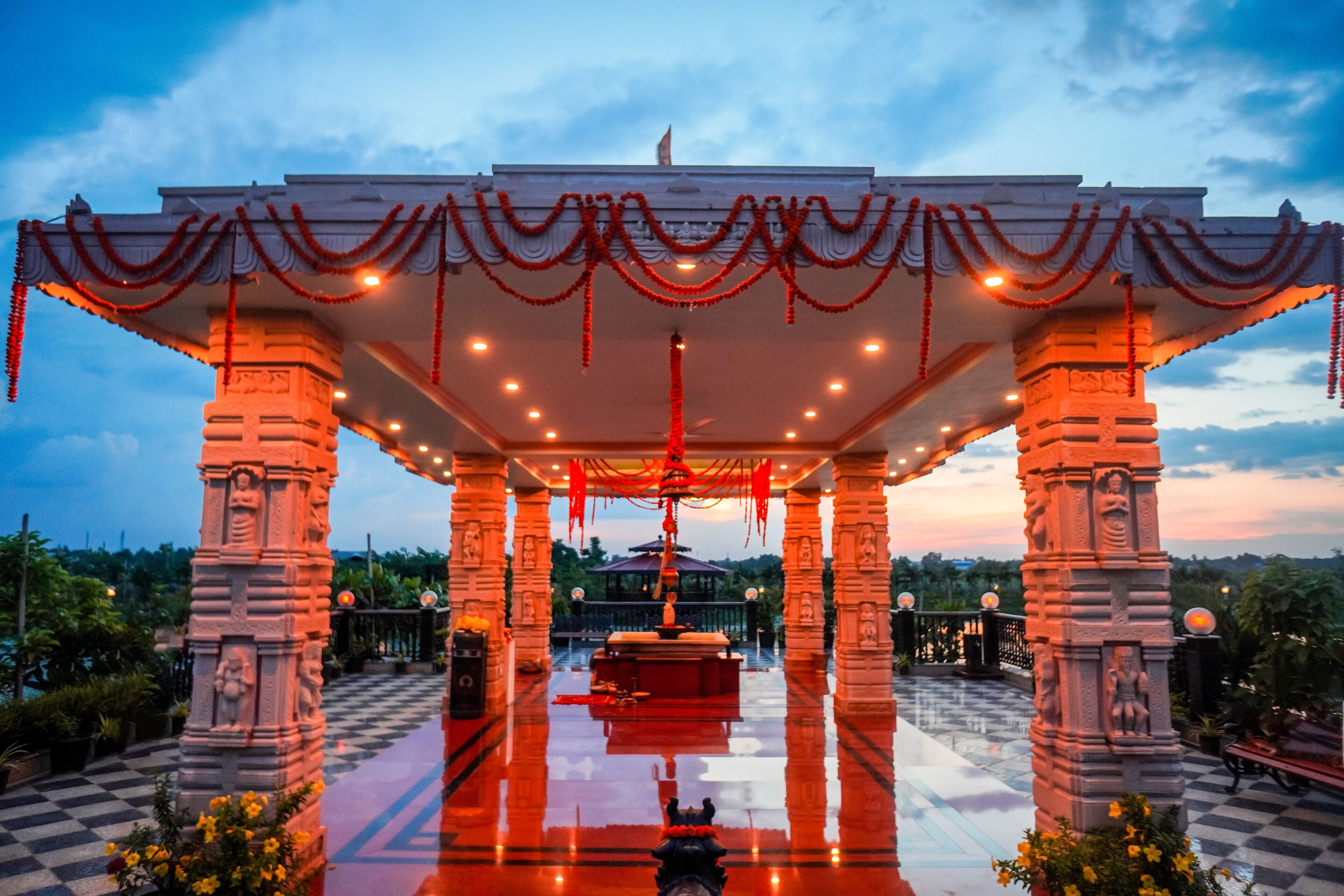 A temple with a central statue, surrounded by columns and a checkered floor, under a decorated canopy.