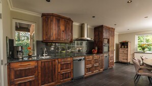 A modern kitchen with dark wooden cabinets, stainless steel appliances, and a large island. - Group House in Twente with Hot Tub (Losser)