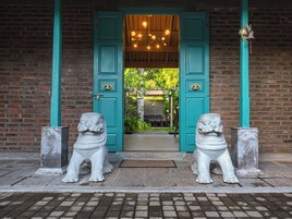 Une entrée d’immeuble ornée de deux statues de lions en pierre, d’une porte de couleur turquoise et d’un mur en briques.