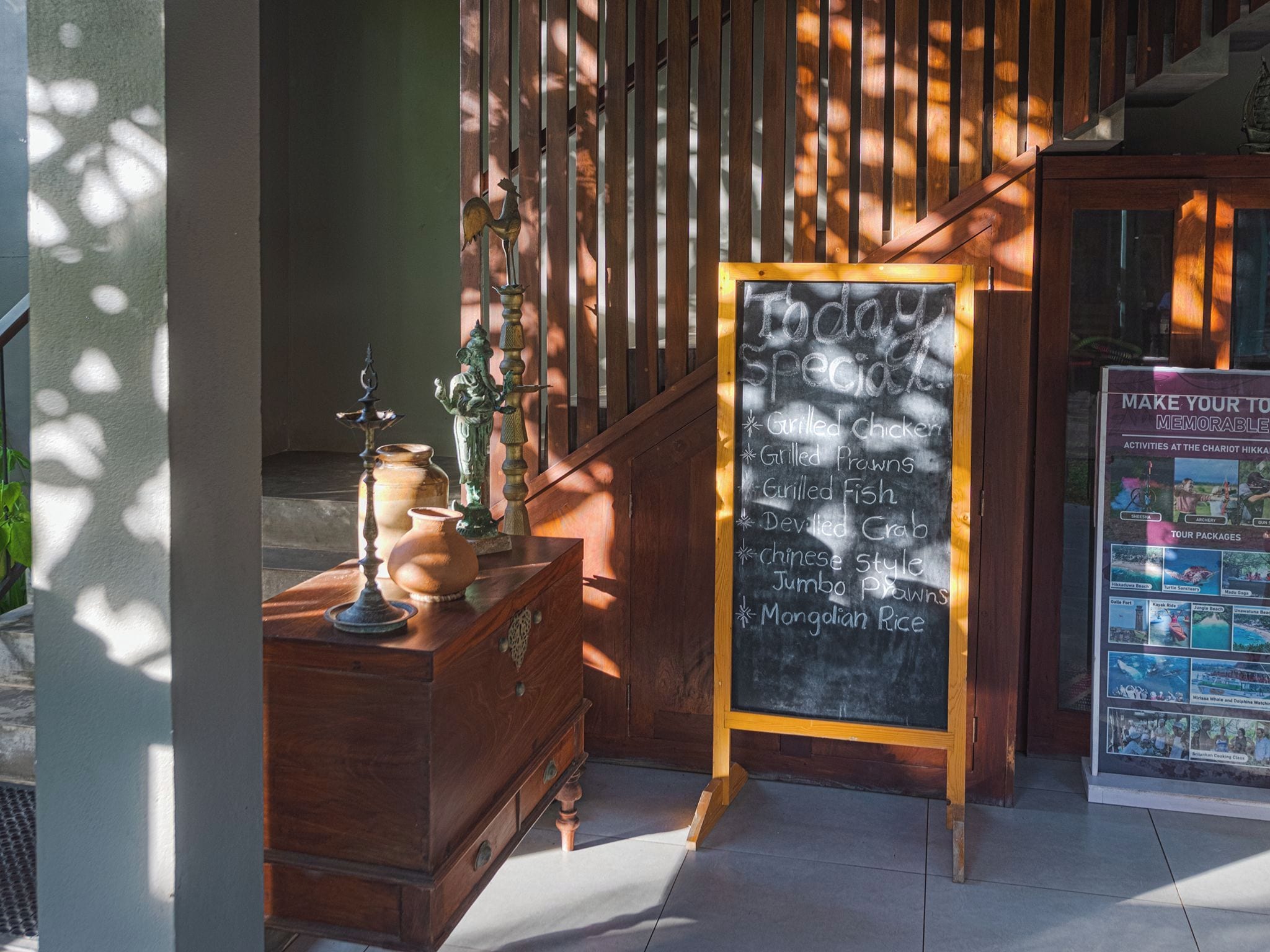 A wooden staircase with a chalkboard menu listing grilled chicken, prawns, fish, crab, and rice.