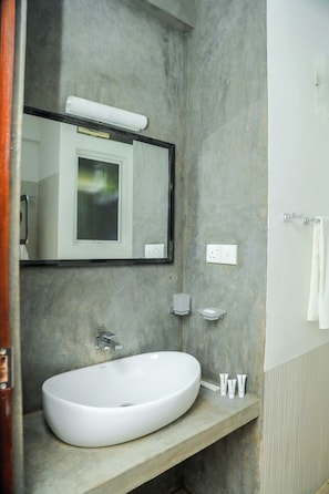 Casa de banho com lavatório branco, espelho e porta-toalhas.